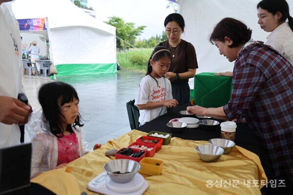 은하 들돌축제 부스에서 아이들이 돌무게 맞추기 체험을 하고 있다. 