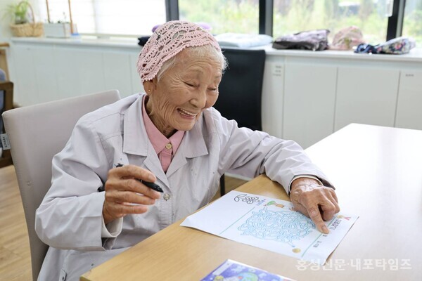 황규순 할머니가 해인노인복지센터에서 그림을 그리며 웃고 있다. 