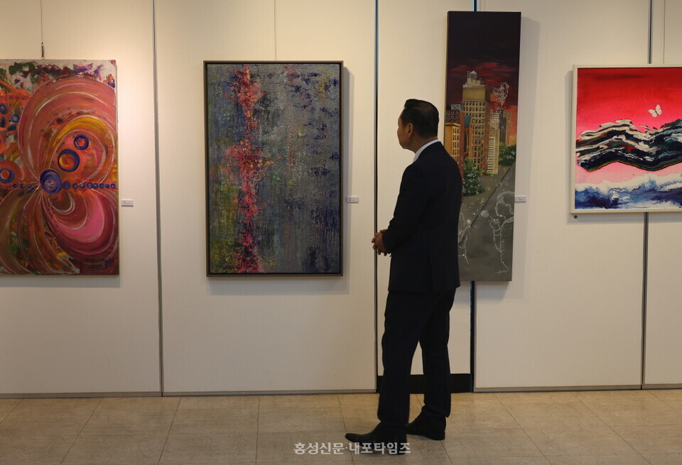 홍성미협 회원전 오프닝 행사 참석자가 작품을 감상하고 있다.