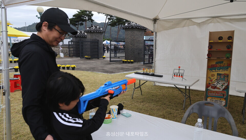 축제장을 찾은 아버지와 아들이 너프건 쏘기 체험에 참여하고 있다.